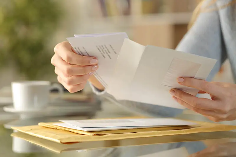 Girl hands opening an envelope on a desk at home