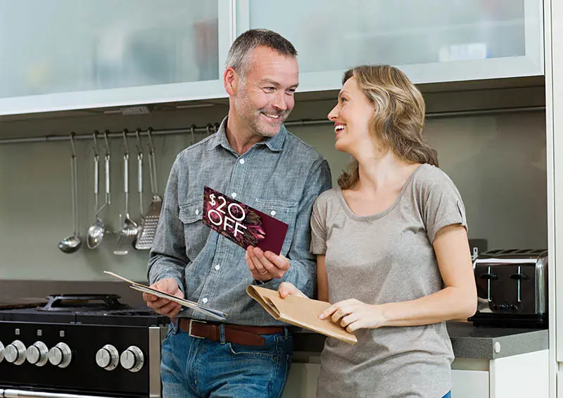 Couple in kitchen holding Direct Mail and smiling