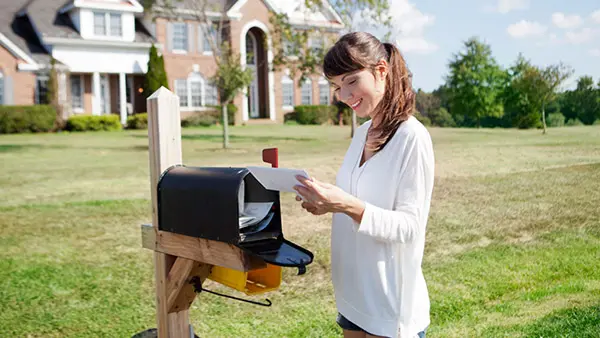 How the Brain Reacts to Print Marketing Webinar - woman reading mail and smiling in front of her mailbox