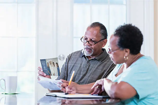 Older couple reading direct mail marketing at the kitchen table
