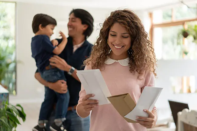 Woman reading direct mail at home with her family in the background